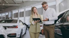 A man talking to a car insurance agent about lowering his car insurance rate. 