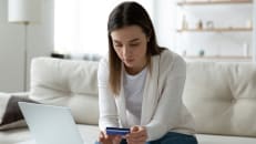 A woman holding her credit card and wondering if it will help her during a recession. 