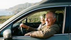 A senior couple driving in their car after learning how they can reduce their premium.