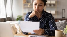 Homeowner reviewing paperwork at her kitchen table to determine if homeowners insurance is tax deductible.