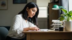 A woman sitting at her desk trying to figure out how long it takes to get a personal loan.