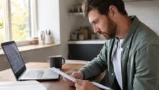 A young adult comparing life insurance quotes on a laptop at home..