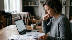 Woman reviewing credit card bills while researching a debt settlement program.