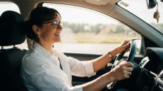A woman driving her car with her minimum state requirements for car insurance.