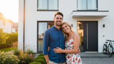 A man and a woman standing in front of their house after learning how to get a lower mortgage rate. 