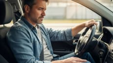 A man sitting in his car wondering why car insurance is so expensive.