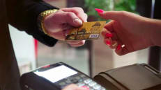 Psychology-of-credit-card-debt: A zoomed in image of a person handing someone their credit card