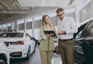 A man talking to a car insurance agent about lowering his car insurance rate. 