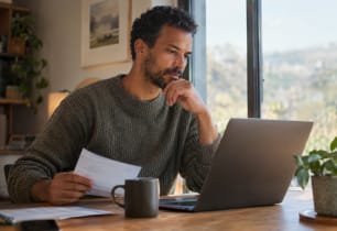 Man reviewing his finances at a home office desk after the Fed rate hike.