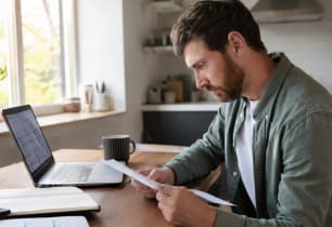 A young adult comparing life insurance quotes on a laptop at home..