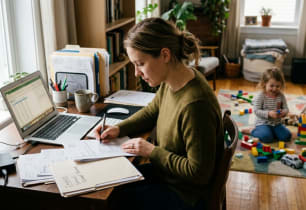 A young parent reviewing term life insurance options at home with their child nearby..