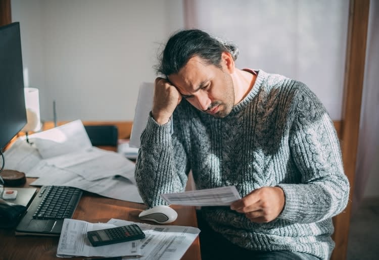 A man sitting at a desk being concerned about a possible forecluse.