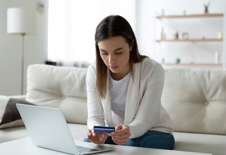 A woman holding her credit card and wondering if it will help her during a recession. 