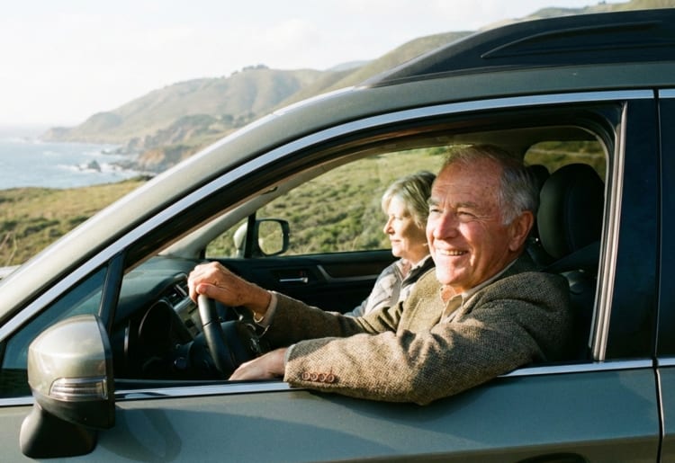 A senior couple driving in their car after learning how they can reduce their premium.