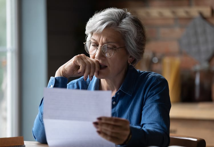 A woman reading a piece of paper with information about debt consolidation vs, bankruptcy.