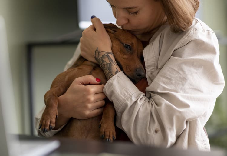 A woman holding her dog in her arms after finding out it has cancer. 