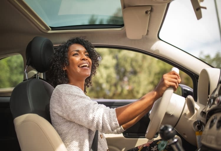 A woman who is a low-mileage driver driving in her car.