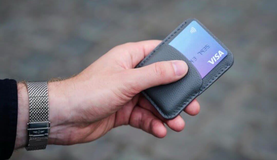 An image of a person holding a wallet with a credit card inside