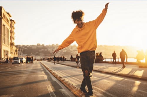 Young man in yellow hoodie happily dancing on the street