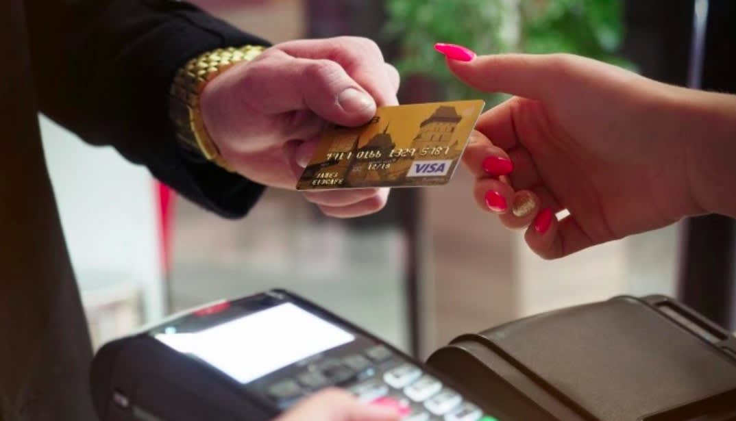 Psychology-of-credit-card-debt: A zoomed in image of a person handing someone their credit card